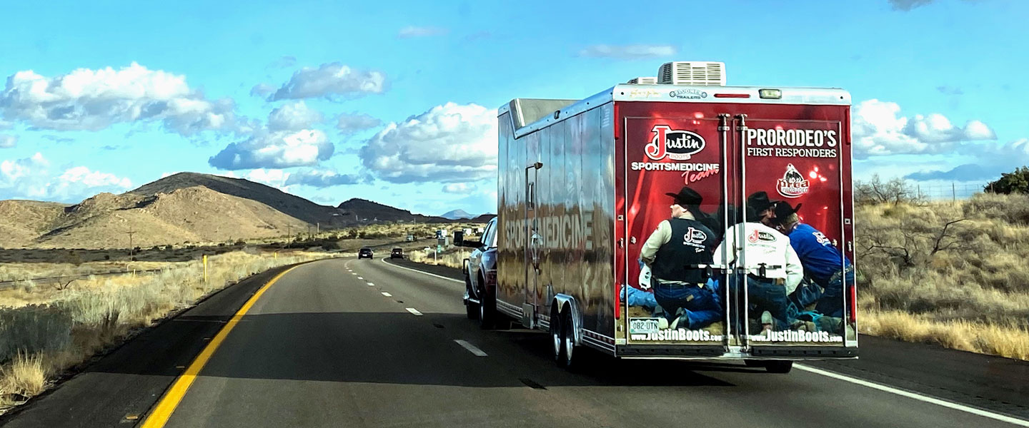 Justin Sportsmedicine® Trailer hauling down the road with a blue sky and mountains.